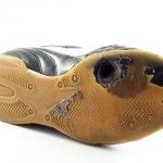 Worn out sports Shoe with hole on bottom, white background.