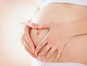 Pregnant Woman holding hands in a heart shape on her baby bump