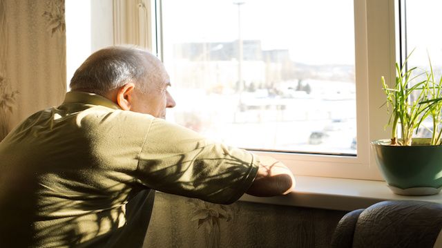 Lonely old man staring out of a window