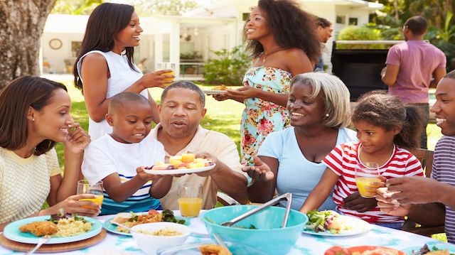 Multi Generation Family Enjoying Meal In Garden Together