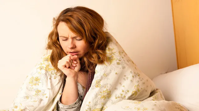 Sick woman cough in ved under blanket