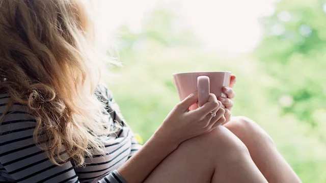Peaceful woman relaxing at home with cup of tea or coffee