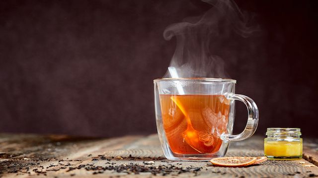 Steaming tea and honey on a wooden table