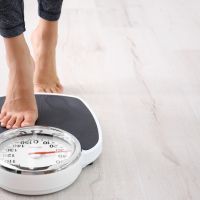 Woman measuring her weight using scales on floor