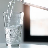 woman pouring down mineral water to glass.