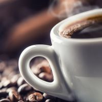 Cup of black coffee with beans on wooden table