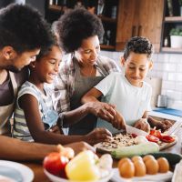 Happy african american family preparing healthy food together in kitchen