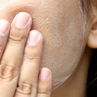 Close up Asia woman cheek. Woman washing face (have wide pores) with white foam by her hand.