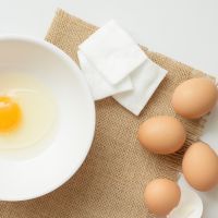 Flat lay of egg white and cotton pad, facial mask for acne skin.